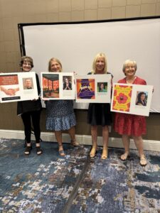 Four women holding posters in conference room