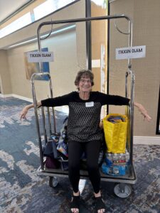 Smiling woman on luggage cart labeled 'Tikkun Olam'