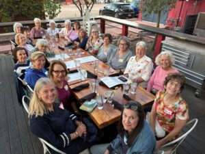 Women gathering around outdoor restaurant table