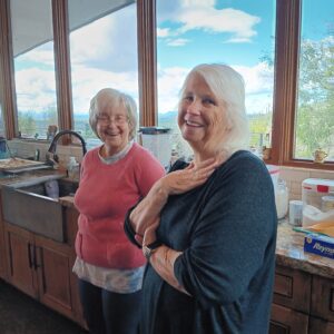 Two smiling senior women in sunlit kitchen