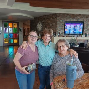 Three women smiling together in a living room