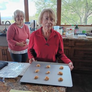 Two smiling seniors arranging cookie dough on tray