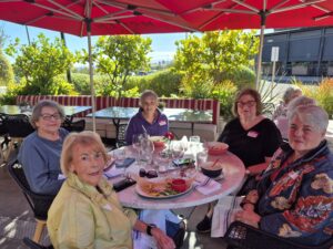 Senior women enjoying outdoor lunch under umbrella