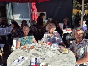 Smiling seniors gathered around sunny café table