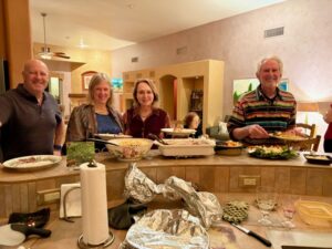 Smiling adults serving buffet across kitchen island