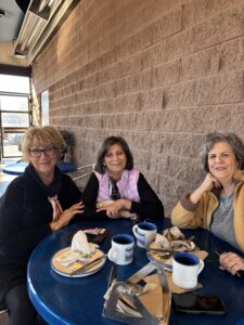 Three women smiling at blue cafe table