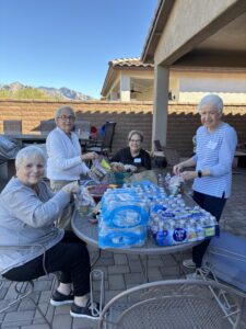 Four women packing bottled water and snacks