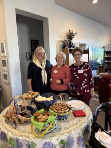 Three women smiling behind snack-filled table