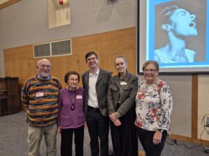 Five adults posing near projected portrait