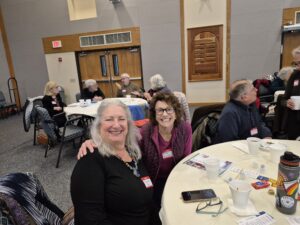 Two smiling women at community meeting table