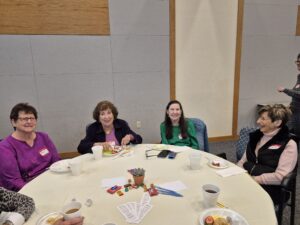 Smiling women seated around table with snacks