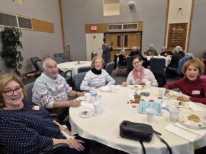 Seniors smiling around table at community luncheon