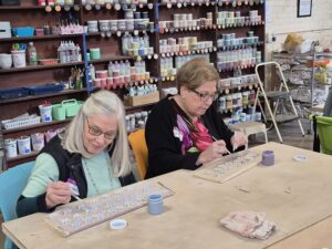 Two women painting decorative tiles in craft studio