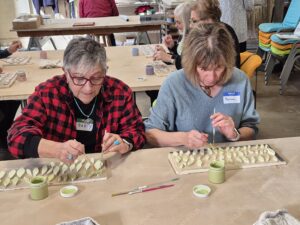 Women painting rows of ceramic leaf tiles