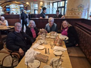 Four adults smiling at restaurant booth