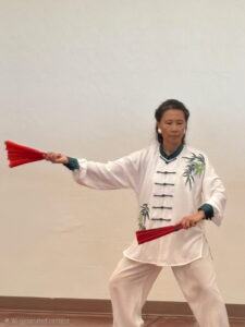 Person performing tai chi with red fans