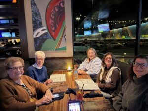Five friends smiling around restaurant table