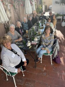 Smiling group dining outdoors at long patio table