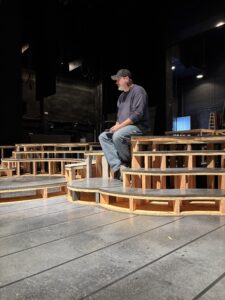 Man seated on wooden theater stage platforms
