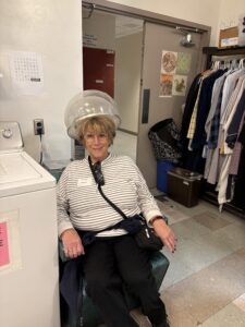 Smiling person seated under salon hairdryer