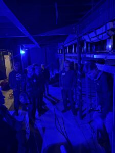 Small group touring blue-lit backstage area