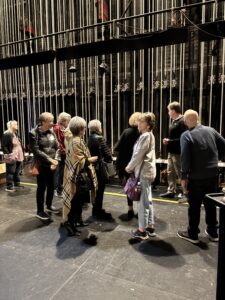 Tour group backstage near theater rigging