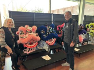 Two people posing with colorful lion dance heads