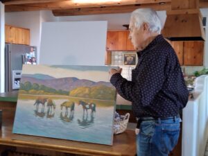 Man holding landscape painting of horses
