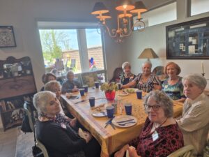 Smiling senior women around sunlit dining table