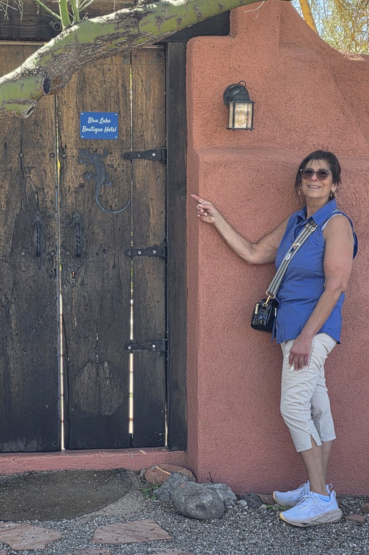 Smiling woman pointing at rustic adobe doorway