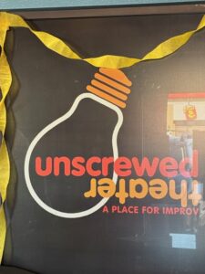 Unscrewed Theater lightbulb logo sign