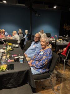 Seniors seated at community dinner with flowers