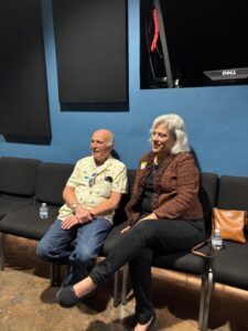 Two seniors seated in blue-walled waiting area