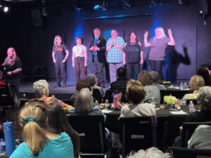 Actors onstage performing for seated dinner audience