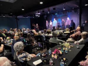 Audience at dinner theater watching performers onstage