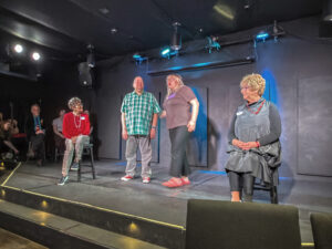 Four actors performing on intimate black-box stage