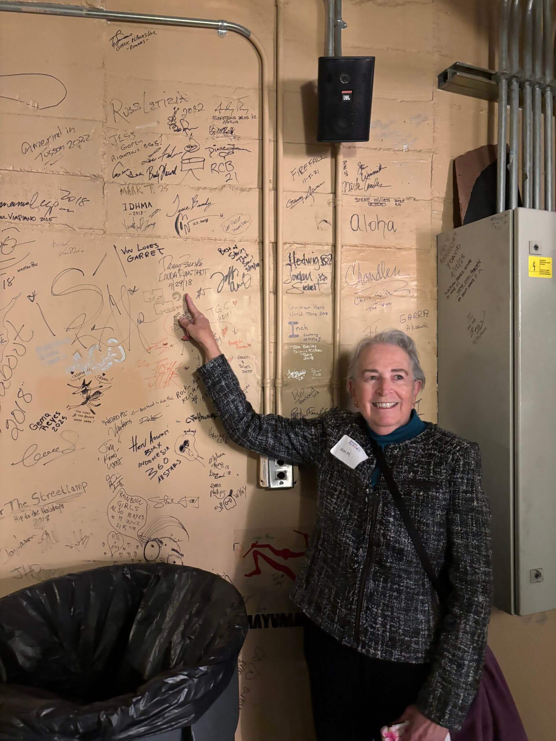 Smiling woman pointing at signature-covered wall