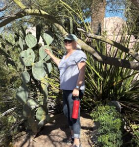 Woman by prickly pear cactus holding red bottle