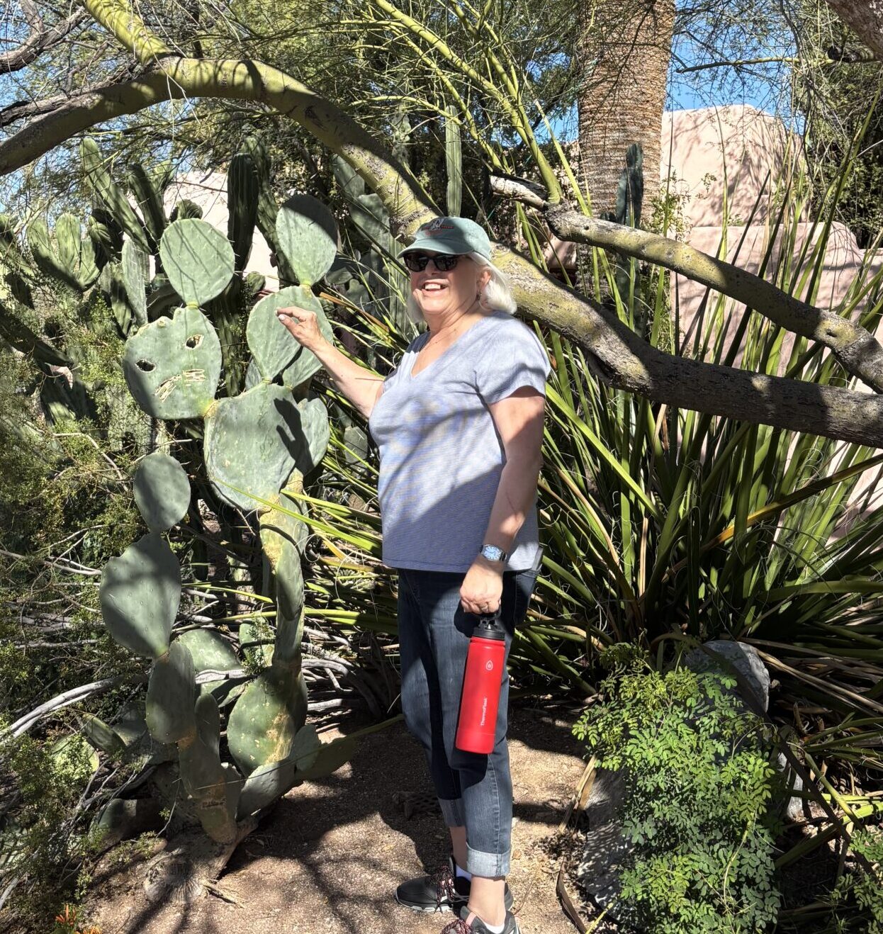 Woman by prickly pear cactus holding red bottle